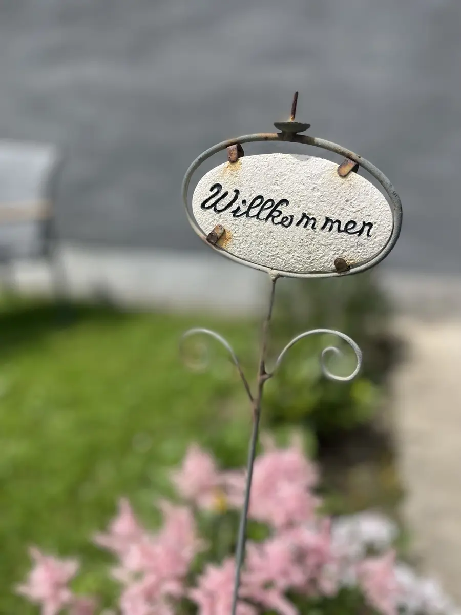 Willkommen-Schild zwischen Blumen in unserem Garten